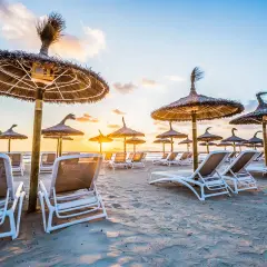 Puste leżaki i parasole na Alcudia Beach o zachodzie słońca. Idealne miejsce na relaks.