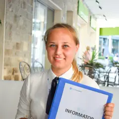 Uśmiechnięta rezydentka z niebieskimi oczami trzyma segregator z napisem "Informator".