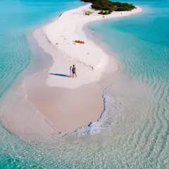 Para na piaszczystej mierzei, idealne miejsce na wycieczkę na Malediwy. W tle pomarańczowa kajak i zieleń wyspy.