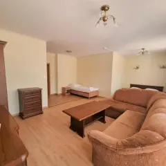 Pokój w Paradiso Park Pobierowo: wygodna kanapa, stolik kawowy, szafa, komoda i łóżka.