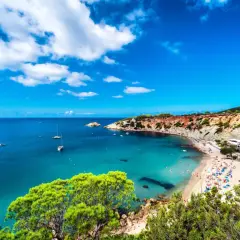 Malownicze zatoczki i plaże na Balearach, z turkusową wodą i żaglówkami na horyzoncie.