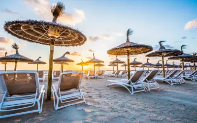 Puste leżaki i parasole na Alcudia Beach o zachodzie słońca. Idealne miejsce na relaks.