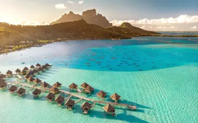 Bora Bora, gdzie jest? Rajskie bungalowy na wodzie w turkusowej lagunie, z górami w tle.