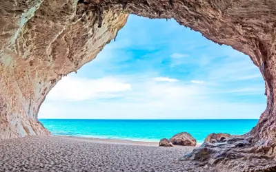 Widok z jaskini na piaszczyste plaże Alghero i turkusowe morze.