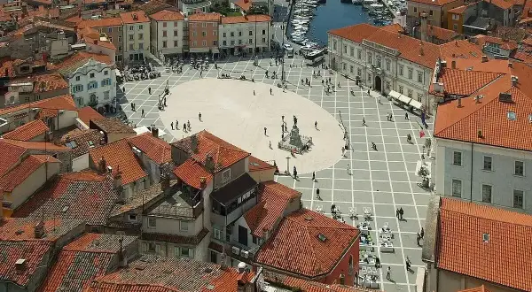 Słowenia morze: malowniczy plac w Piran, z widokiem na dachy i port.