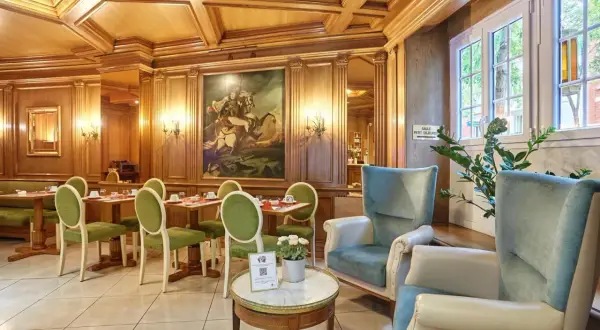Elegancka jadalnia w hotelu Murat z zielonymi krzesłami i obrazem konnym.