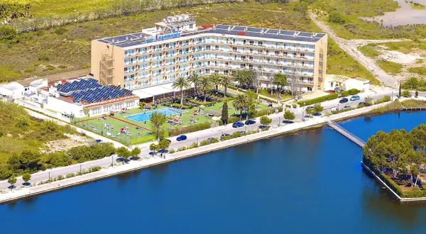 Hotel Tui Suneo Lagomonte z basenem i panelami słonecznymi, położony nad błękitną wodą.