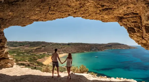 Para w jaskini podziwia widok na turkusowe morze i plażę. Malta pogoda kwiecień idealna na zwiedzanie.