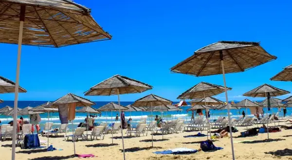 Słoneczna plaża w Bułgarii, pełna leżaków i parasoli. Ludzie odpoczywają, ciesząc się wakacjami. Czy w Bułgarii jest bezpiecznie? Tak, to popularny i bezpieczny kierunek turystyczny.