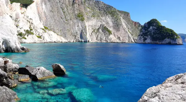 Turkusowe wody Zatoki Wraku, otoczone białymi klifami, tworzą malowniczy krajobraz w okolicach miasta Zakynthos.