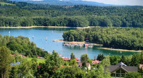 Piękna pogoda w Bieszczadach, nad Soliną w Polańczyku. Jezioro pełne żaglówek, otoczone zielonymi lasami i domkami.