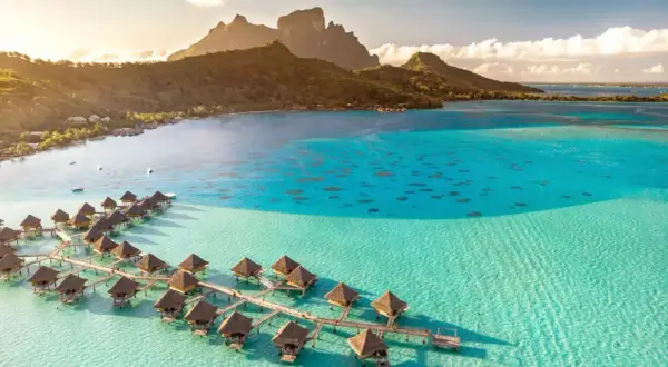 Bora Bora, gdzie jest? Rajskie bungalowy na wodzie w turkusowej lagunie, z górami w tle.