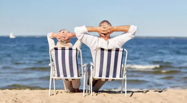 Para seniorów cieszy się wczasy nad morzem z dojazdem z Katowic, relaksując się na plaży.