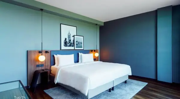 Nowoczesny pokój w **Radisson Blu Hotel Rostock** z wygodnym łóżkiem, dwoma obrazami na ścianie i stylowymi lampami.