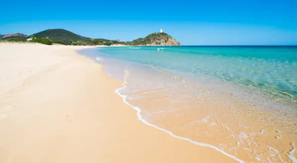 Piękne plaże Cagliari z turkusową wodą i złotym piaskiem. W oddali widać wzgórze z wieżą.