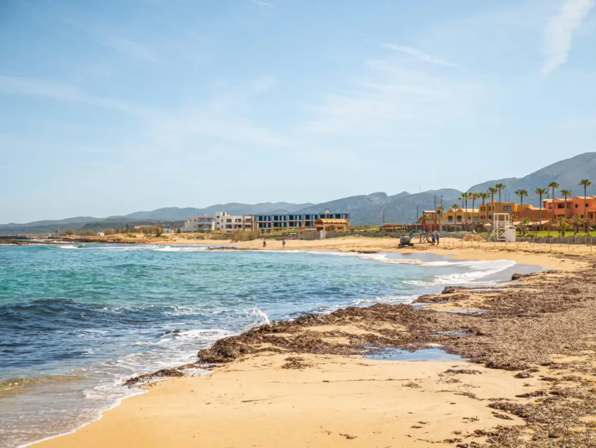 Piękne heraklion plaże z turkusową wodą i piaszczystym brzegiem, w tle hotele i góry.