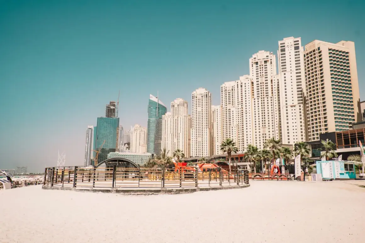 Plaża z widokiem na drapacze chmur, gdzie jest Dubaj. Palmy i nowoczesna architektura tworzą miejski krajobraz.