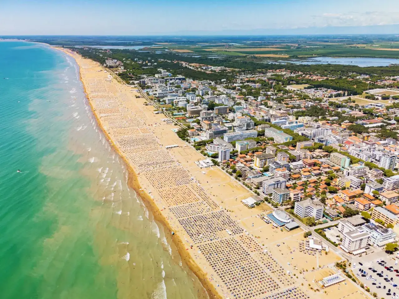 Słoneczna plaża w Bibione tętni życiem. Tysiące leżaków i parasoli tworzą barwny dywan, a turkusowe morze zaprasza do kąpieli.