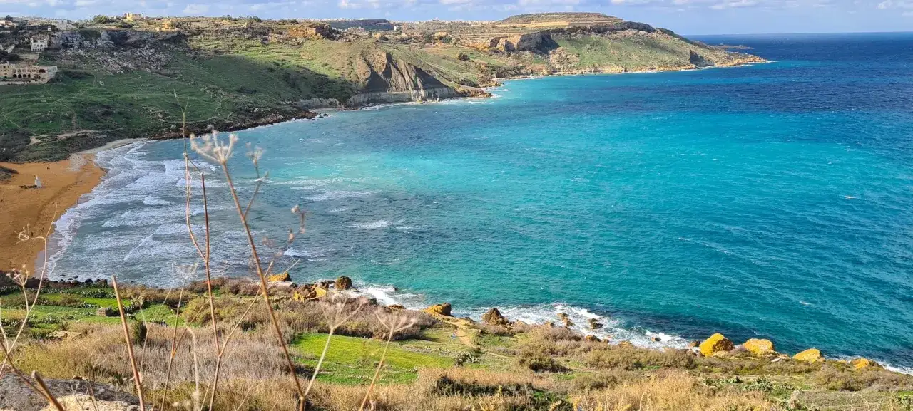Malta, z turkusowym morzem i piaszczystą plażą. Czy na Malcie są rekiny? W tych pięknych wodach raczej nie spotkasz ich na powierzchni.
