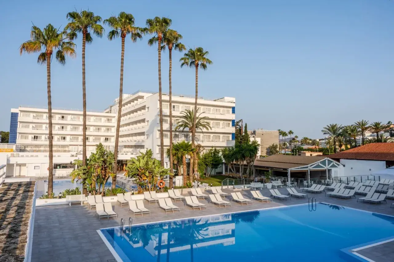 Relaks przy basenie w hotelu TUI Suneo Santa Ponsa. Palmy i leżaki zapraszają do odpoczynku.